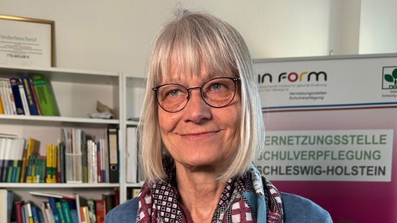Frau steht vor einem Bücherregal und einem Aufsteller mit der Aufschrift Vernetzungsstelle Schulverpflegung Frau steht vor einem Bücherregal und einem Aufsteller mit der Aufschrift Vernetzungsstelle Schulverpflegung © NDR Foto: Daniela Tabarelli