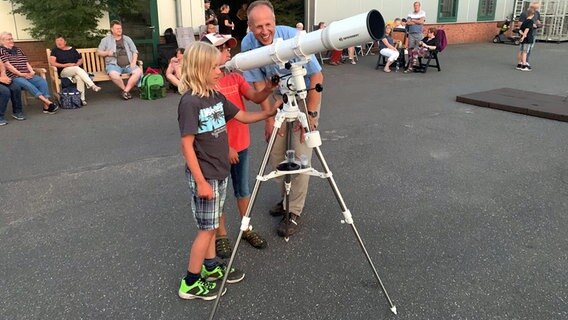 Zwei Jungen und ein Mann stehen vor einem Teleskop auf dem Geländer der Regionalen Volks-und Schulsternwarte Tornesch e. V. Zwei Jungen und ein Mann stehen vor einem Teleskop auf dem Geländer der Regionalen Volks-und Schulsternwarte Tornesch e. V. © NDR Foto: Lena Haamann