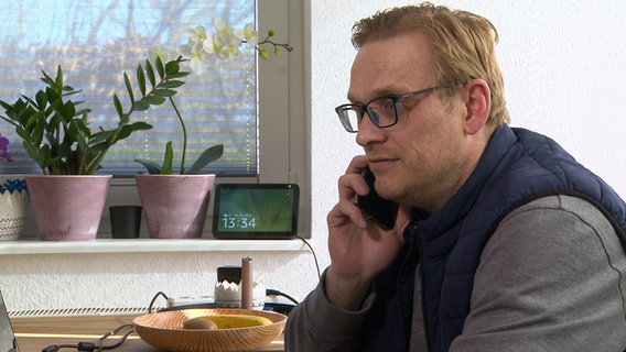 Sprachlehrer Markus Peuser telefoniert in seinem Wohnzimmer auf Fehmarn. © NDR 