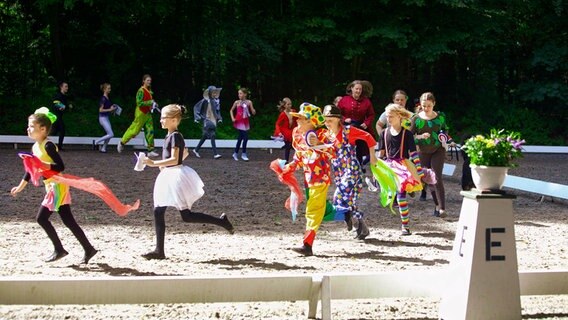Verkleidete Kinder rennen im Kreis auf einer Reitsportfläche. © Pferdesportverband Schleswig-Holstein e.V. Foto: Stefan Stuhr