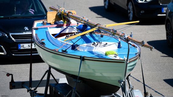 Ein Auto mit einem Segelboot auf einem Anhänger steht auf der Autobahn A1 bei Ratekau im Stau. © dpa-Bildfunk Foto: Jonas Walzberg