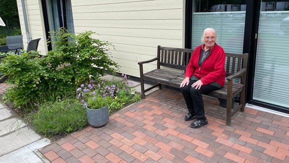 Eine Frau lächelt, auf einer Bank auf einer Terrasse sitzend, in die Kamera © Berit Ladewig Foto: Berit Ladewig