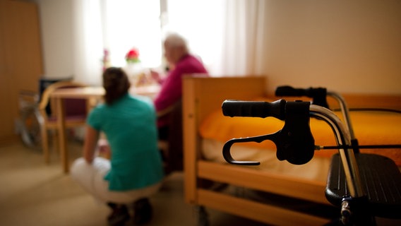 Eine Pflegefachkraft hilft einer älteren Dame in einem Seniorenheim. © picture alliance Foto: Arno Burgi