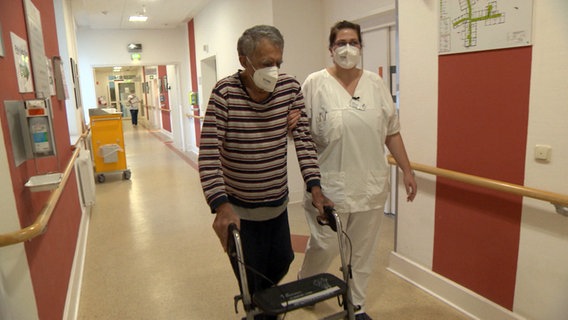 Eine Pflegerin begleitet einen Patienten auf den Gängen des St. Elisabeth Krankenhaus in Eutin. © NDR 