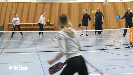 Menschen spielen in einer Turnhalle Pickleball. © NDR 