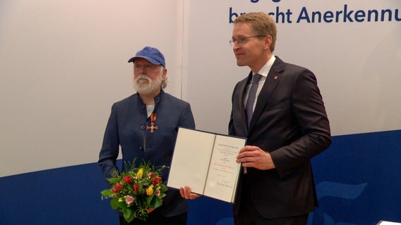 Minsterpräsident Daniel Günther (CDU) übergibt Burghard Pieske das Bundesverdienstkreuz. © NDR 