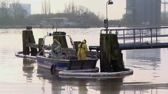 Zwei Einsatzkräfte des THW stehen auf einem Einsatzboot am NOK in Brunsbüttel nach einem Pipeline-Leck. © NDR 