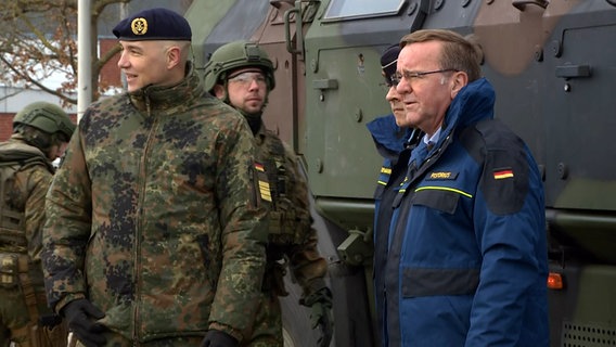 Verteidigungsminister Boris Pistorius (SPD) steht neben Marineoffizieren beim Ankunft auf dem Marinestützpunkt in Eckernförde. © NDR 