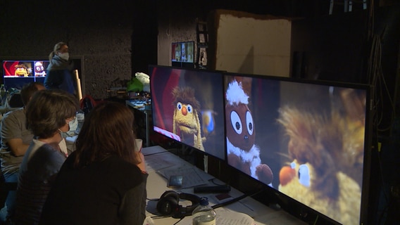 Zwei Menschen beobachten über Bildschirme die Produktion von "Pittiplatsch".  