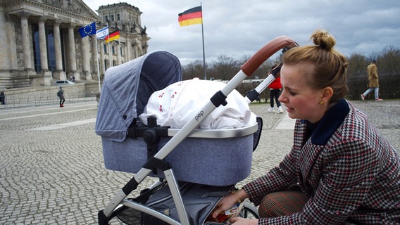 Frau kniet vor einem Kinderwagen © NDR Foto: Lornz Lorenzen