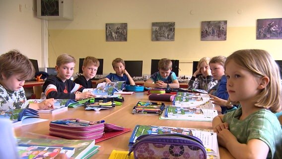 Kinder sitzen an einem Tisch und lernen Plattdeutsch. © NDR 