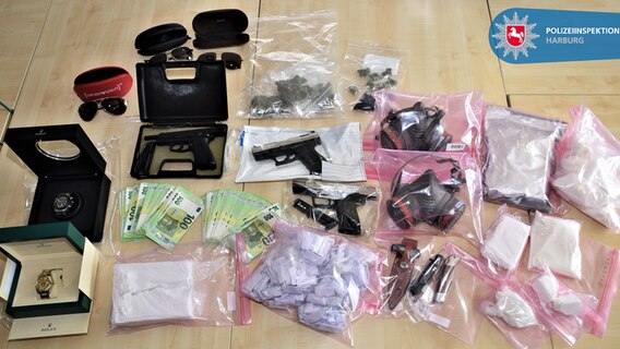 Ein Auszug sichergestellter Drogen und Wertgegenständen liegen in Plastiktüten verpackt auf einem Tisch © Polizeiinspektion Harburg 