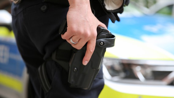 Ein Polizist hält seine Hand auf seiner geöffneter Dienstwaffe im Halfter am Gürtel. © NDR Foto: Pavel Stoyan