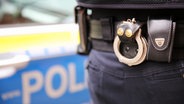 Handschellen hängen am Gürtel eines Polizisten. © NDR Foto: Pavel Stoyan