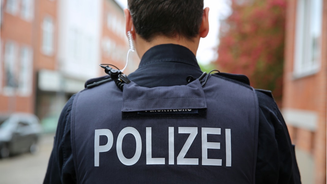 Schriftzug Polizei steht auf dem Rücken an der Uniform eines Polizisten.