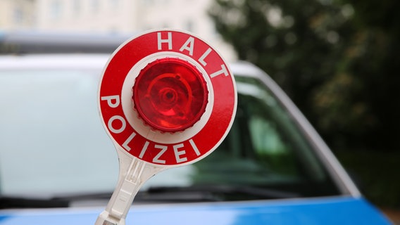 Ein Polizist hält eine Polizeikelle vor einem Streifenwagen. © NDR Foto: Pavel Stoyan