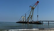 Am Timmendorfer Strand wird ein unter einer Seebrücke verkeilter Ponton von einem bergungskran geborgen © NDR Foto: Tobias Gellert