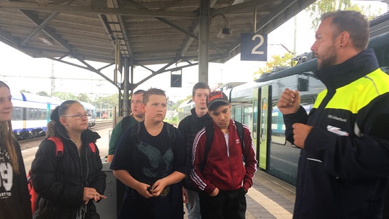 Ein Mann aus dem Präventionsteam der Deutschen Bahn steht auf einem Bahnsteig vor einer Gruppe Kindern © NDR Foto: Christiane Stauss