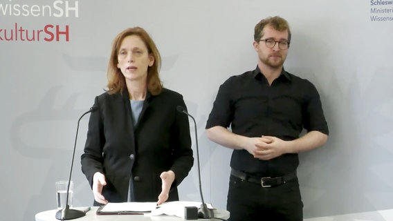 Bildungsministerin Karin Prien mit Gebärdendolmetscher bei einer Pressekonferenz. © Ministerium für Bildung, Wissenschaft und Kultur Foto: Screenshot YouTube