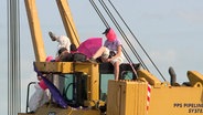 Demonstrierende sitzen auf einem Bagger. © NDR Foto: NDR Screenshots