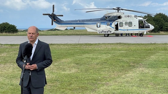 Bundeskanzler Olaf Scholz steht in Putlos vor einem Mikrofon, hinter ihm ein Helikopter der Luftwaffe © NDR Foto: Christian Wolf