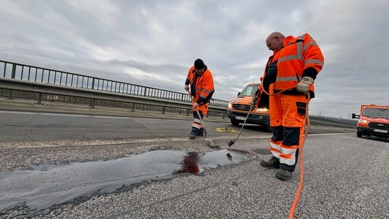 Arbeiter reparieren Schlaglöcher in der Fahrbahn der Rader Hochbrücke auf der A7. Arbeiter reparieren Schlaglöcher in der Fahrbahn der Rader Hochbrücke auf der A7. © NDR Foto: Tobias Gellert