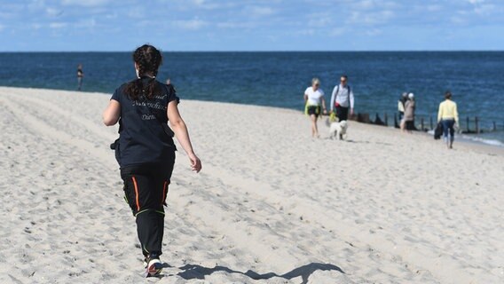 Eine Frau läuft über einen Strand. © NDR Foto: Jörn Zahlmann