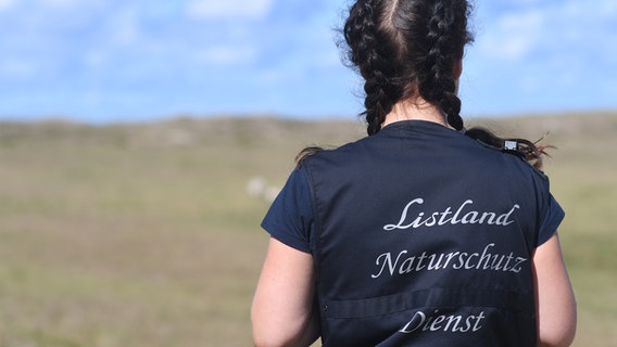 Auf dem Rücken einer Rangerin steht Listland Naturschutz Dienst. © NDR Foto: Jörn Zahlmann