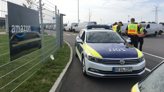 Zollbeamte stehen bei einer Razzia auf dem Gelände der Firma Amazon in Bad Oldesloe © NDR Foto: Helge Albrecht