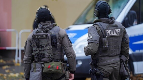 Zwei Beamter des SEK stehen vor einem Polizeibus bei einer Razzia. © picture alliance / Flashpic Foto: Jens Krick