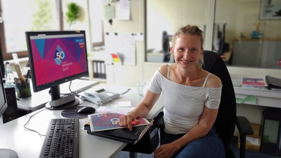 Eva Reiners von der Stadtpark GmbH sitzt an ihrem Schreibtisch und lächelt in die Kamera. © NDR Foto: Sabine Alsleben