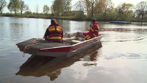 Wasserrettungsboot mit zwei Personen in Uniform an Board schwimmt auf dem Wasser. Wasserrettungsboot mit zwei Personen in Uniform an Board schwimmt auf dem Wasser.