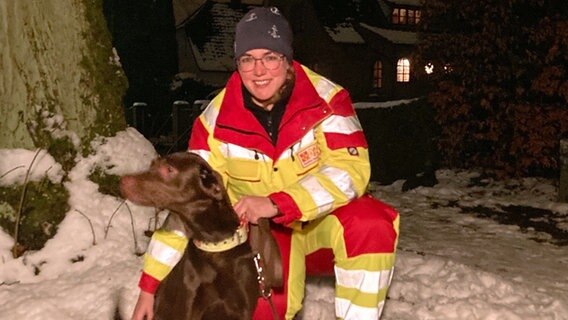Der Rettungshund und seine Ausbilderin zusammen draußen im Schnee. © NDR Foto: Christiane Stauss