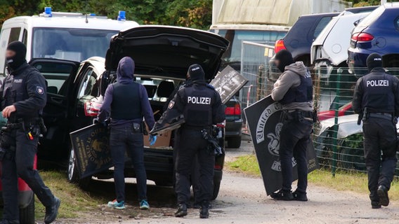 Polizeibeamte räumen Gegenstände der Razzia in ein Auto. © Danfoto Foto: Danfoto
