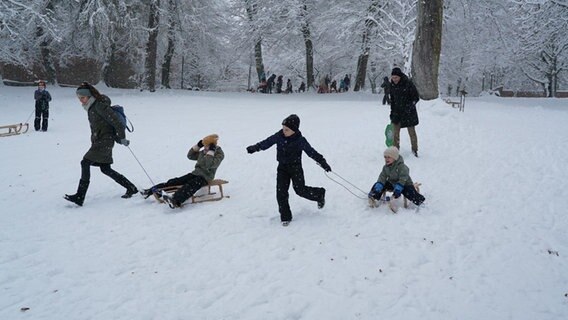 Eine Familie fährt mit zwei Schlitten durch den Schnee. © Daniel Friederichs 