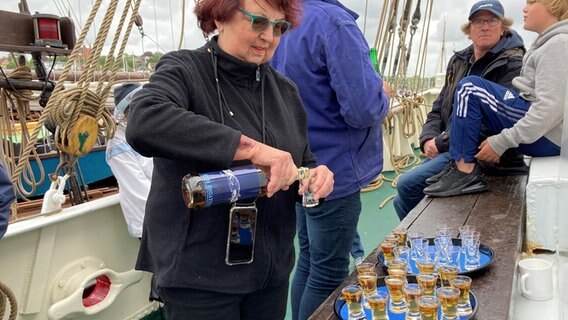 Eine ältere Dame schenkt Schnäpse aus, während der Rum-Regatta in Flensburg.  Foto: Simone Mischke