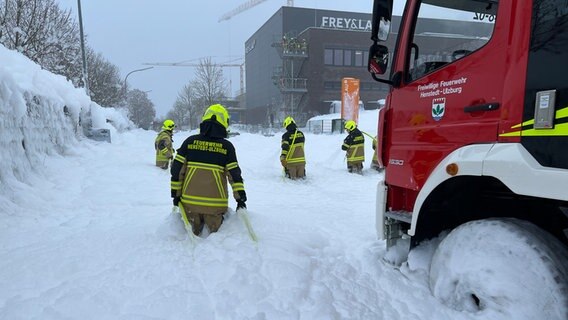 Mitglieder der Feuerwehr laufen durch hüfthoch liegenden Löschschaum. © Westküsten-News Foto: Florian Sprenger