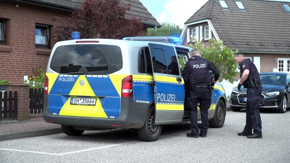 Zwei bewaffnete Pilizisten stehen an einem Einsatzfahrzeug im Kieler Stadteil Elmschenhagen. © TeleNewsNetwork 