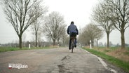 Ein Fahrradfahrer fährt auf einer kaputten Straße © NDR 