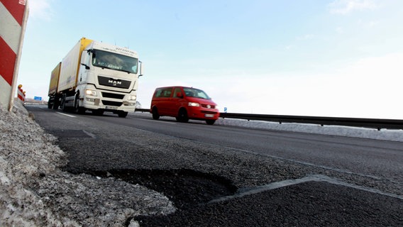 Ein Schlagloch auf einer Autobahn, mit fahrenden Autos im Hintergrund. Ein Schlagloch auf einer Autobahn, mit fahrenden Autos im Hintergrund. © Imago Images
