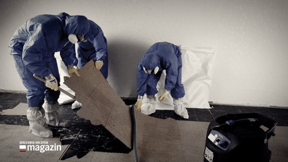 Drei Personen in Schutzanzügen entfernen Asbest aus einem Gebäude. © NDR 