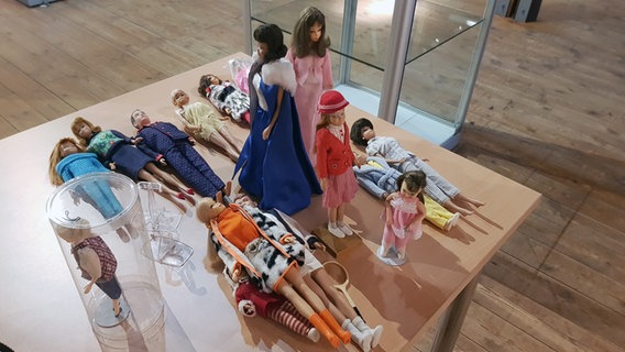 Die Puppen der Busy Girl Ausstellung liegen auf einem Tisch verteilt. © NDR Foto: Jörn Schaar