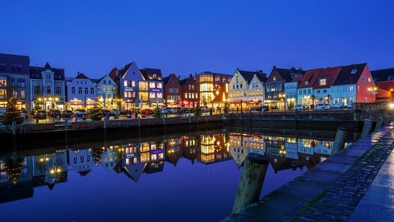 Häuser am Husumer Hafen spiegeln sich zur blauen Stunde im Wasser des Hafenbeckens. © Bernd Schwennen Foto: Bernd Schwennen