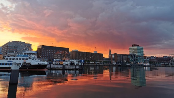 Am Hafen liegen Schiffe. Im Hintergrund sind die Gebäude der Stadt. Die letzten Sonnenstrahlen erläuchten den bewöllten Himmel in sanften Farben. © Charlotte Haugg Foto: Charlotte Haugg