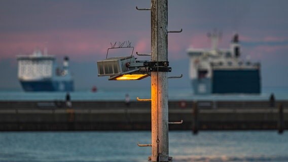 Eine Laterne markiert den Rand der Trave, zwei Fähren im Hintergrund © Michael Adelhardt Foto: Michael Adelhardt