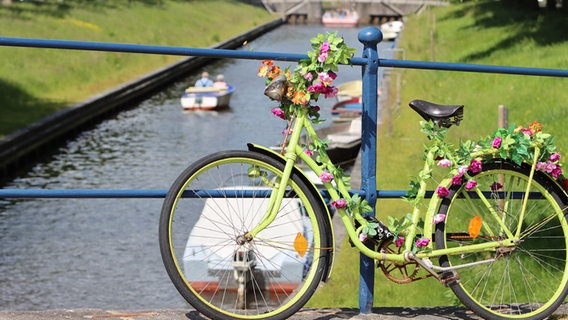 Ein mit Blumen umwickeltes Fahrrad lehnt am Geländer einer Brücke über dem Wasser. © Sebastian Müller Foto: Sebastian Müller