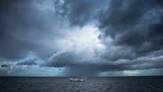 Ein kleines Fischerboot auf dem Meer im Hintergrund eine große dunkle Wolkenfront. © Karin Bräunert Foto: Karin Bräunert