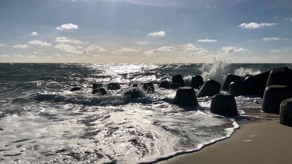 Das Wasser schlägt an die Tetrapoden bei Hörnum-Odde und eine Spieglung der Sonne ist auf dem Meer zu sehen. © Cornelia Göricke-Penquitt Foto: Cornelia Göricke-Penquitt