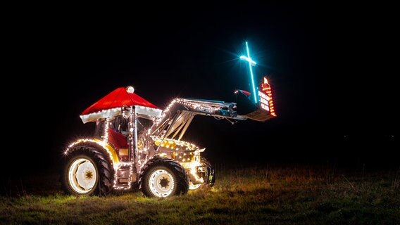 Ein weihnachtlich geschmückter Trecker mit vielen Lichtern und einer Weihnachtsmannmütze. © Armin Reichhardt Foto: Armin Reichhardt