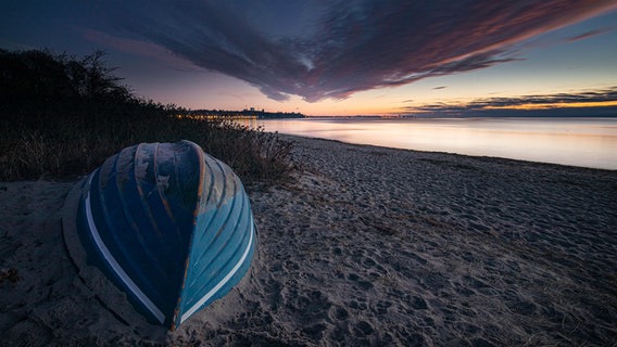 Ein Holzboot liegt auf einem Sandstrand. © Michael Adelhardt Foto: Michael Adelhardt